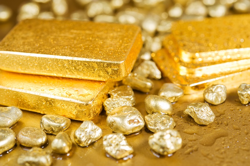 fine gold ingots and nuggets on a wet golden background ** Note: Shallow depth of field